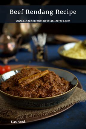Beef rendang in a dark bowl with yellow rice in the background